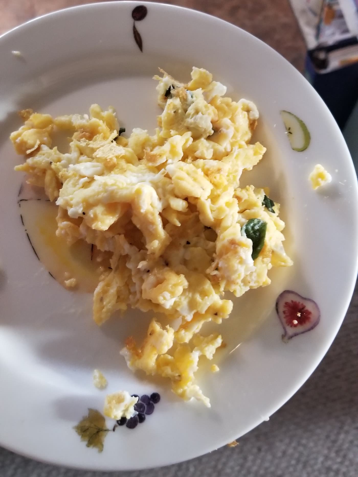 Soft scrambled eggs with torn basil leaves on a white plate